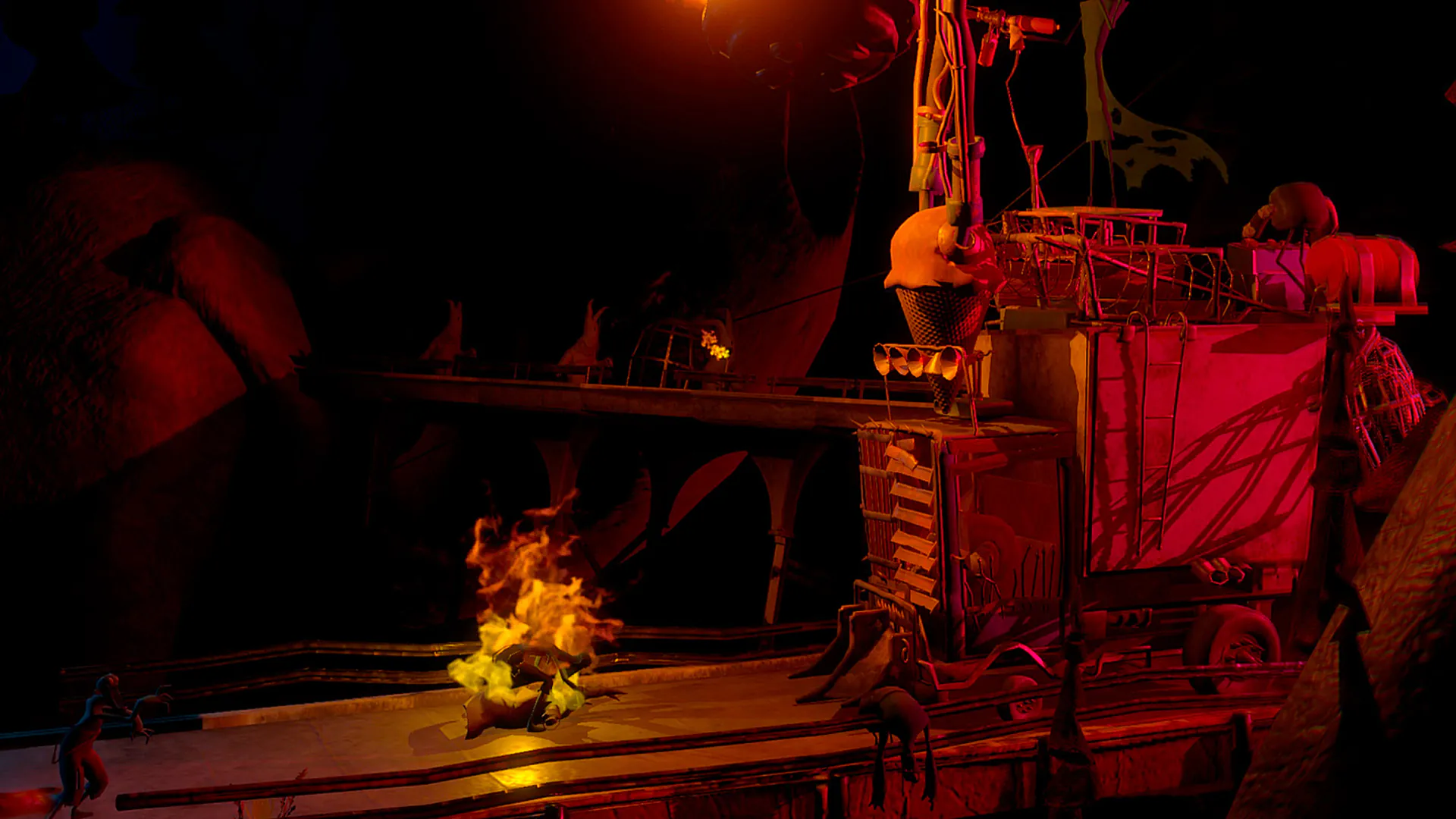 Une machine de bois et de métal surmontée d'une flamme, dans une pénombre orangée